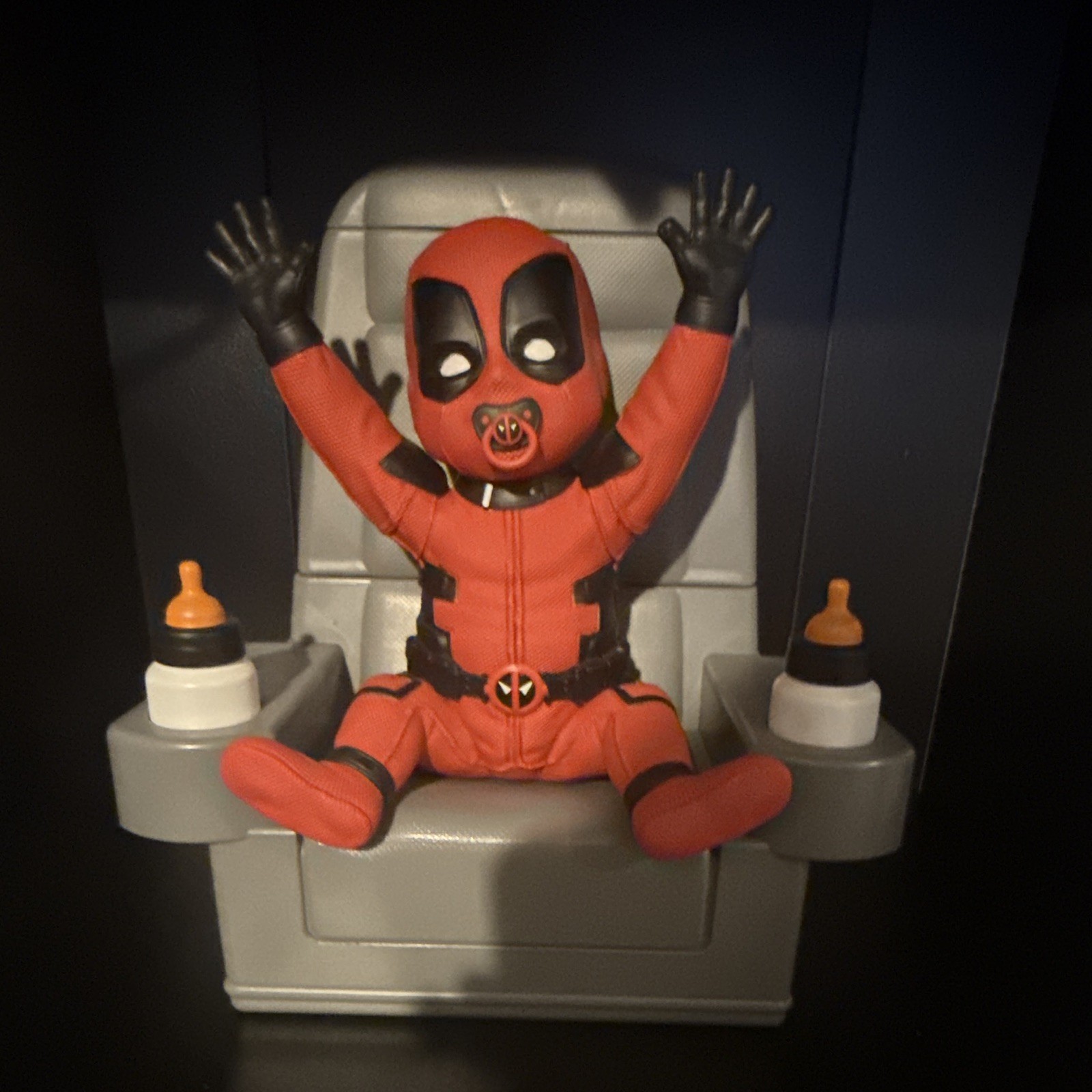 Deadpool Plastic Action Figure Sitting in Gray Chair, Red/Black/White